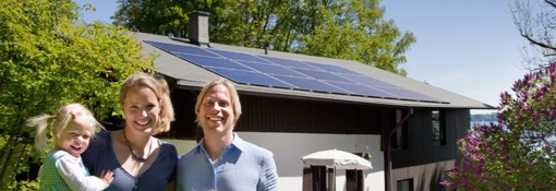 Family standing in front of house with solar panels on the roof